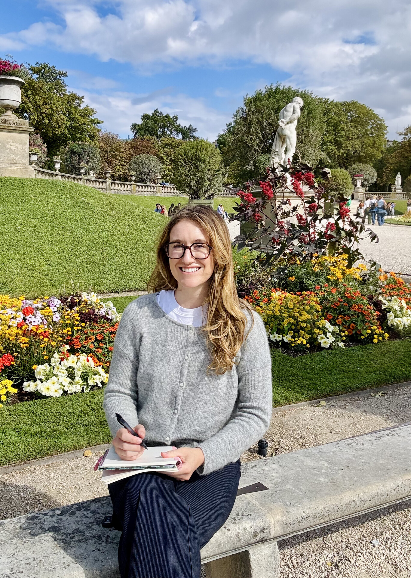 Amy Franks seated on a green bench in a Parisian garden