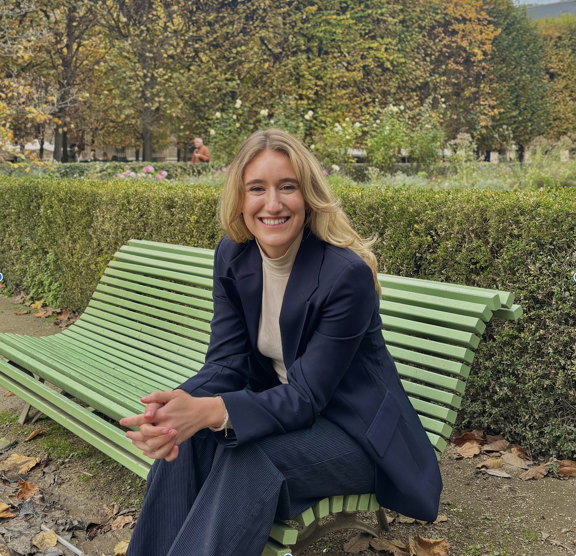 Amy Franks seated on a green bench in a Parisian garden